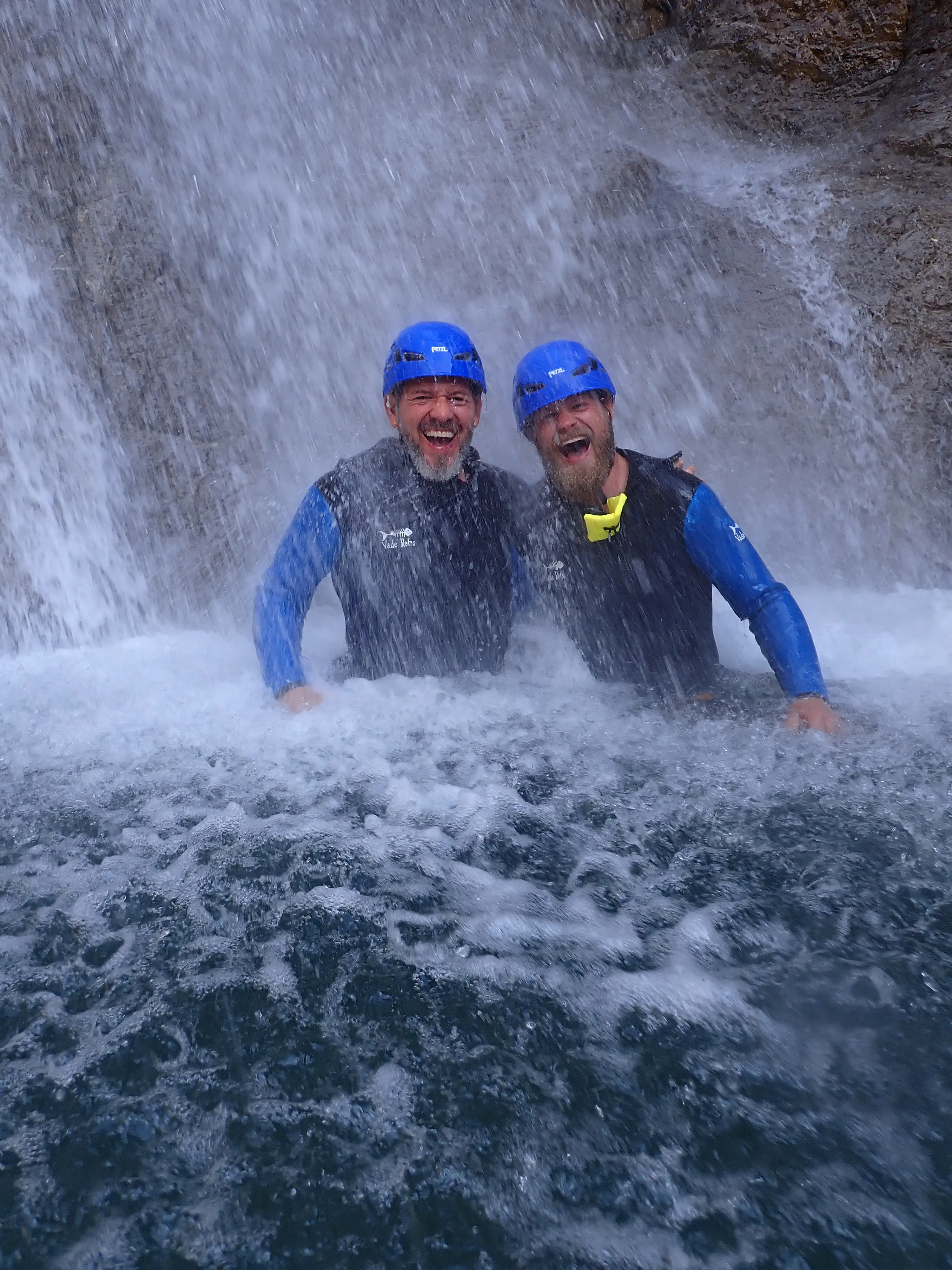 Zwei lachende Männer im Sprühnebel des Wasserfall